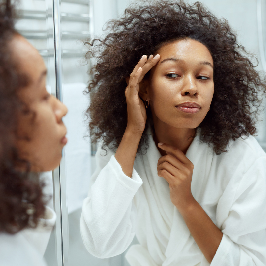 Woman looking at her face in the mirror