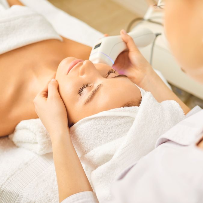 woman laying on a treatment table receiving a facial skin treatment