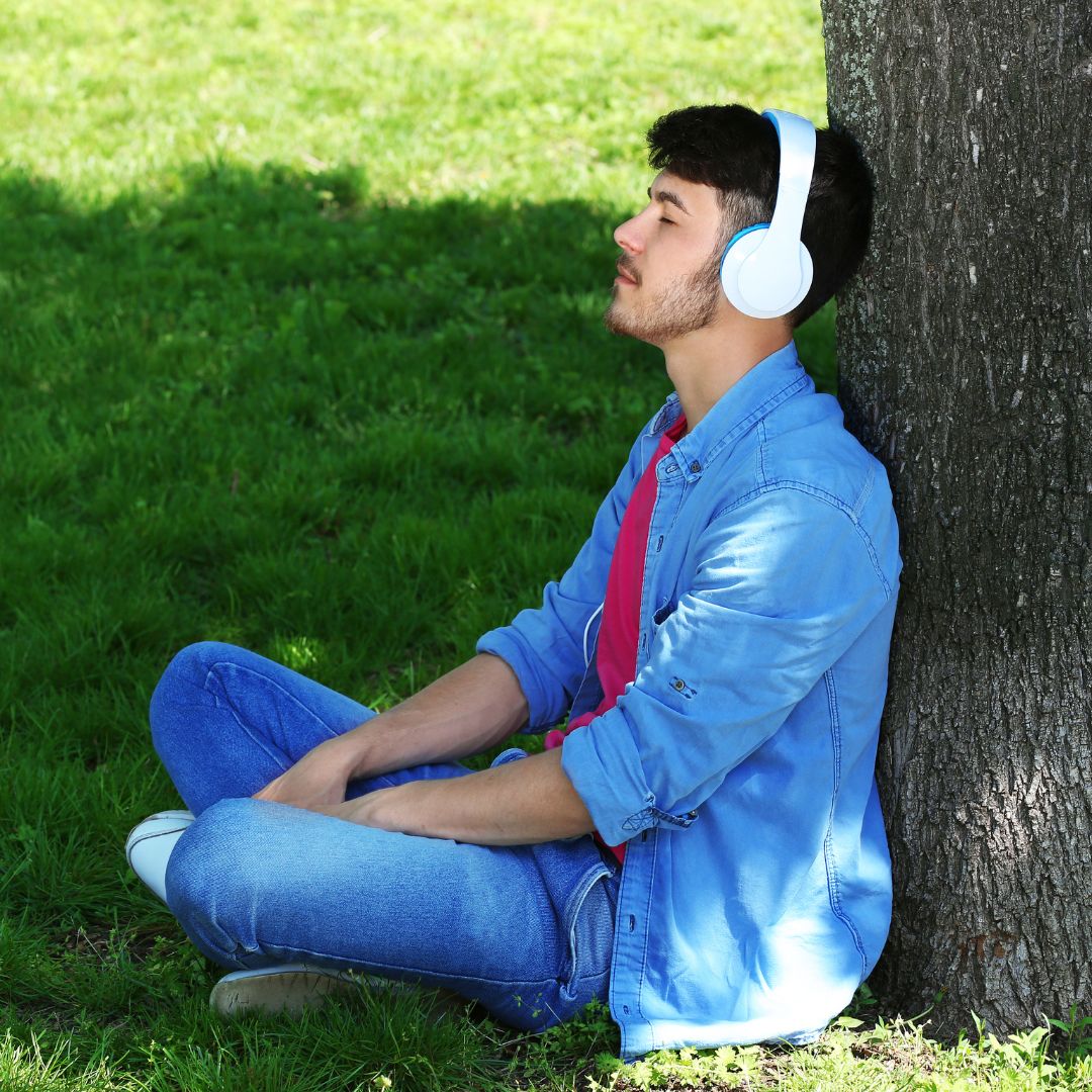 man sitting under a tree listening to music
