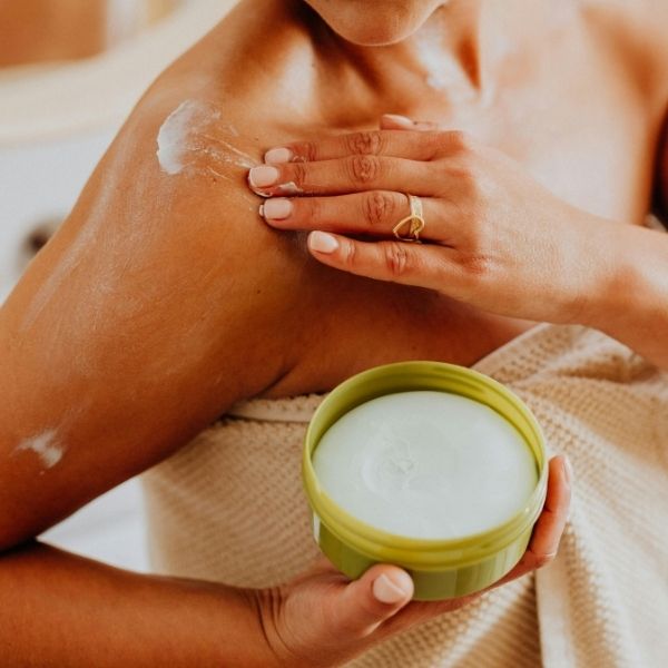 woman in towel applying cream to skin